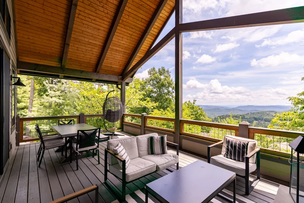 Here, an outdoor seating area equipped with comfortable chairs and hanging seating overlooks a breathtaking mountain vista. The setting is serene and welcoming, ideal for relaxing with family, friends, or pets and soaking in the natural beauty and social atmosphere of the resort.
