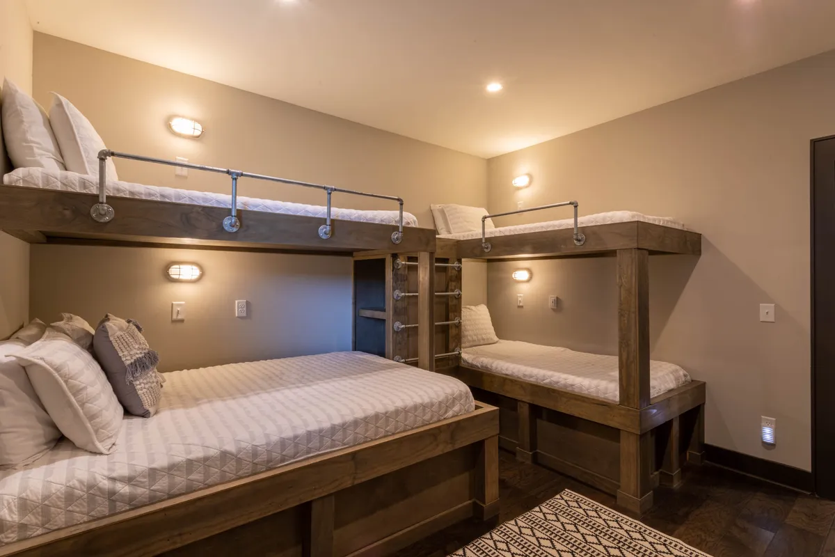A family-friendly bunk room with sturdy wooden bunk beds, textured bedding, and welcoming wooden furniture. The space exudes warmth and togetherness, ideal for late-night storytelling, reading, or playing games as a group.