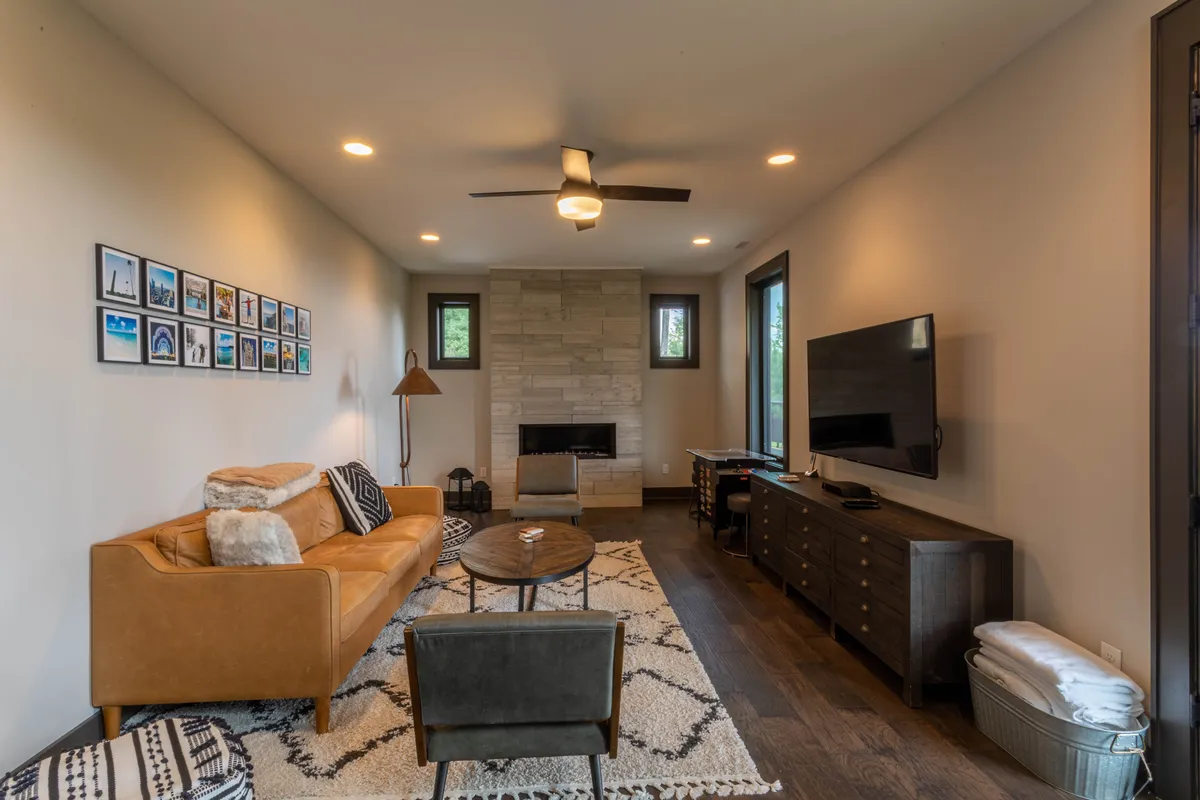 A cozy living space with a leather sofa, a contemporary fireplace, a TV console, and art displayed on the wall. The room exudes warmth and modern comfort, ideal for gatherings or relaxing evenings.