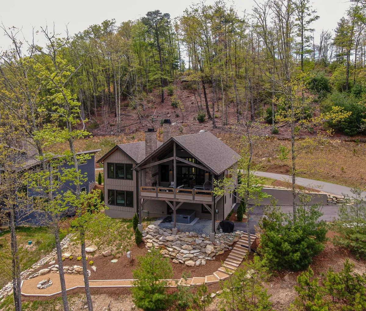A serene exterior view of the house nestled among tall trees with a landscaped yard. The peaceful surroundings are ideal for outdoor relaxation, nature walks, and enjoying sunset views from the porch.